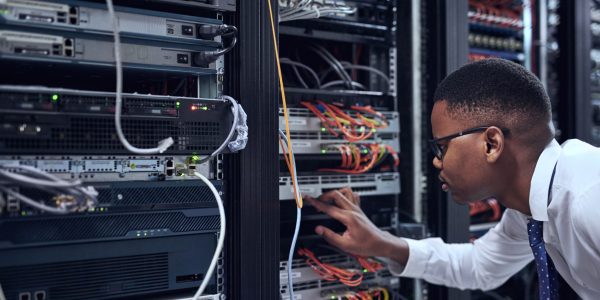 Black man, IT technician and server room for cyber security, data or network storage inspection. African male person or networking administrator checking system, cables or installation at datacenter.